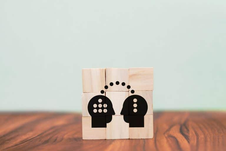 Illustration de deux blocs en bois avec une tête de chaque côté et un lien entre les deux, symbolisant un partage de savoirs